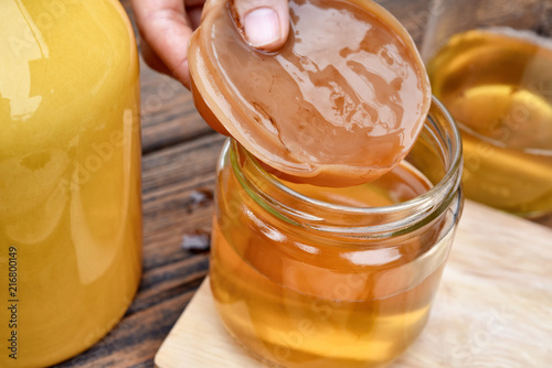 Scoby, Hand holding tea mushroom with kombucha tea, Healthy fermented food, Probiotic nutrition drink for good balance digestive system. photo