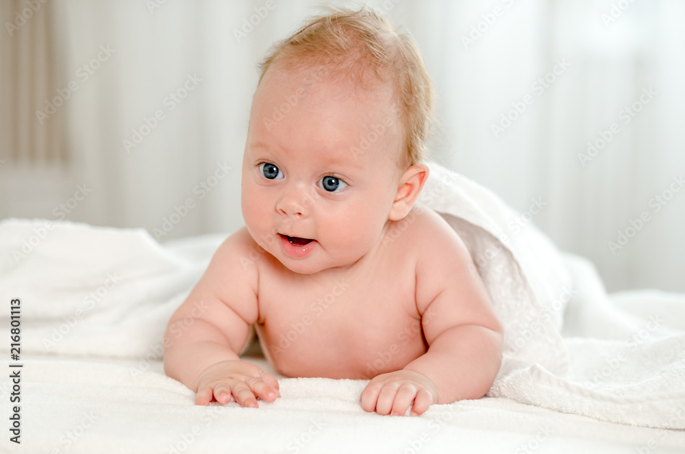 Newborn baby with beautiful blue eyes lying on belly