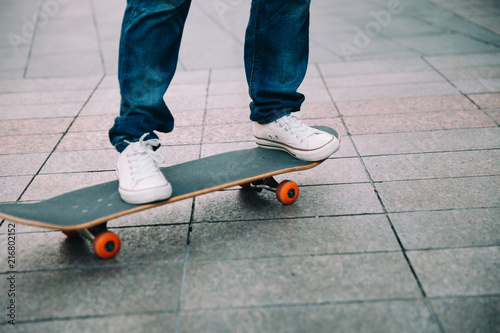 Skateboarder legs riding skateboard on city street