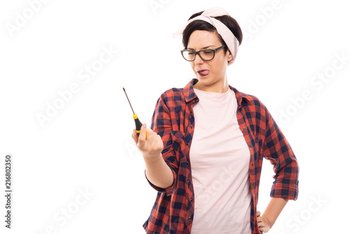 Young pretty pin-up girl looking at screwdriver.