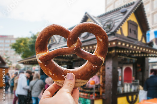 Photography A girl or a young woman is holding a traditional German pretzel in the street