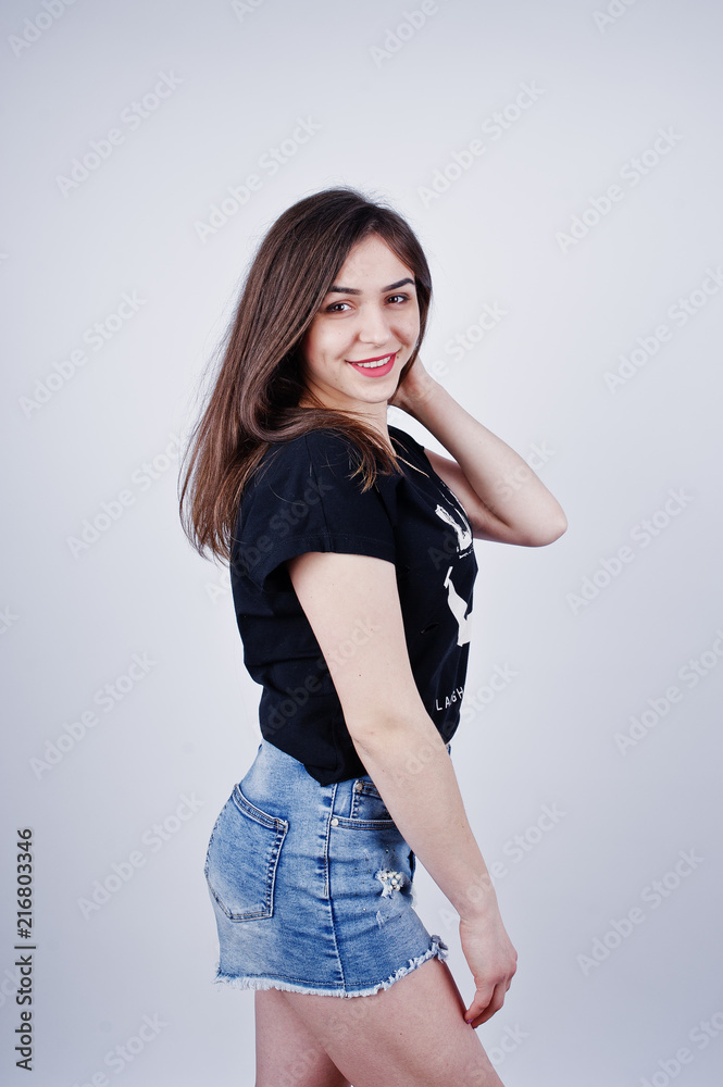 Portrait of an attractive girl in black t-shirt saying lol and denim shorts posing in the studio. Portrait of an attractive girl in black t-shirt saying lol and denim shorts posing in the studio.