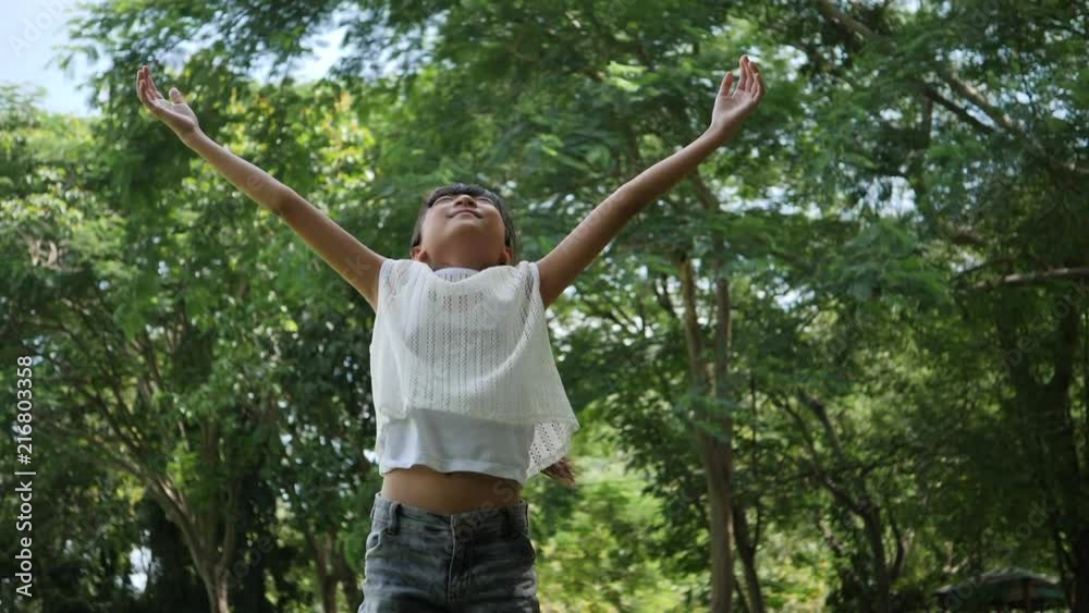 Asian little girl playing outdoor in slow motion, Spinning and smiling and raising hands in the air Asian little girl playing outdoor in slow motion, Spinning and smiling and raising hands in the air