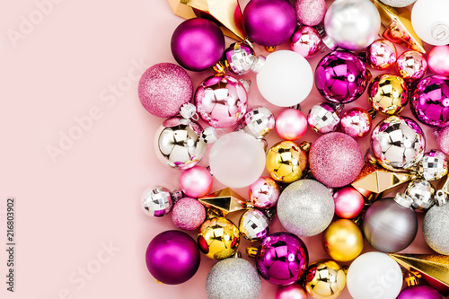 Holiday arrangement with Stylish Christmas shiny baubles and gold crystals on pastel pink background. Flat lay, top view