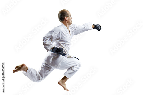 A man in black gloves trains a punch with his hand in a jump isolated