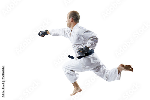 Athlete in black gloves trains a punch with his hand in a jump isolated