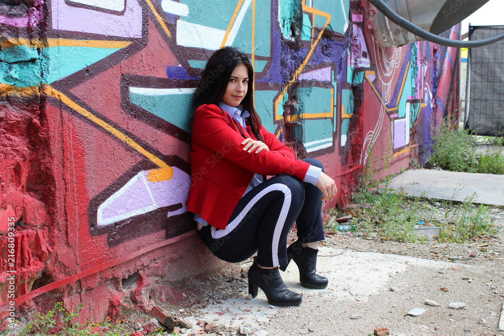 Fashion Portrait - Young Woman leaning against Wall with Graffiti