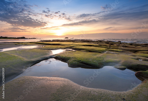 sunset seascape with beautiful rocks formation covered by green moss. soft focus due to long expose. s