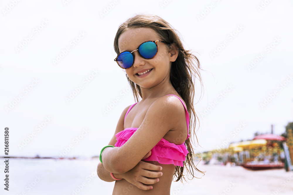 Bimba con occhiali da sole sulla spiaggia Stock Photo | Adobe Stock