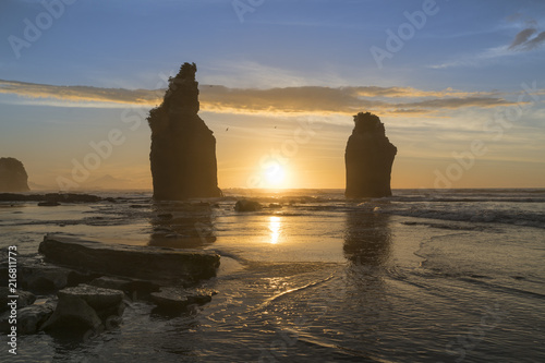 The sun in setting down behind the Three Sisters. Tongaporutu, New Plymouth district. Taranaki region, North Island, New Zealand. photo