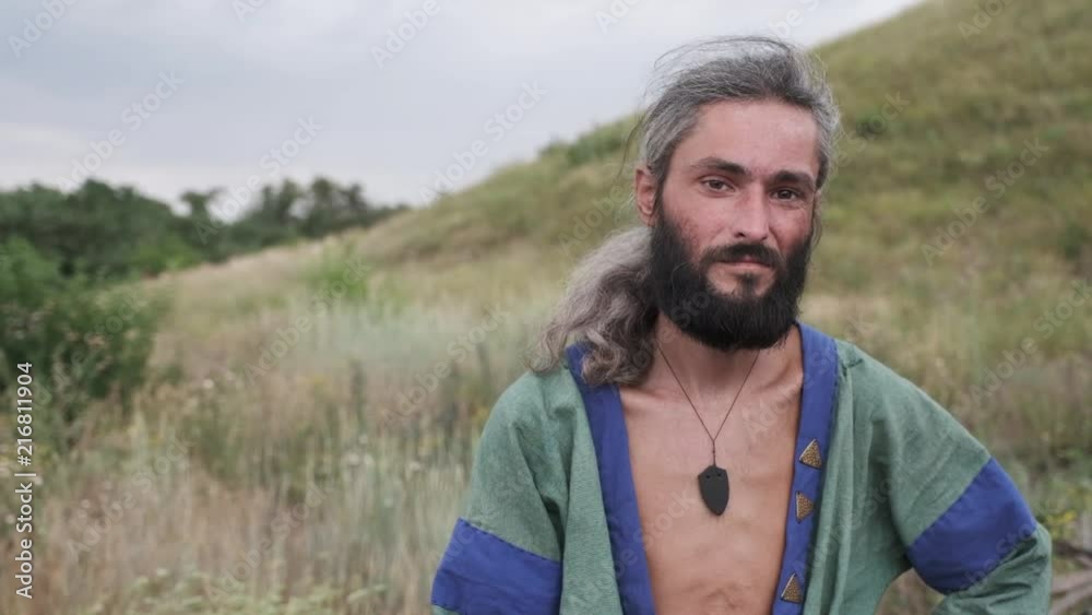 A man in ethnic costume stands in a field and looks away thoughtfully A man in ethnic costume stands in a field and looks away thoughtfully