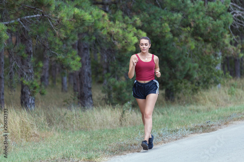Young woman running on forest trail to lose weight and maintaining healthy life.