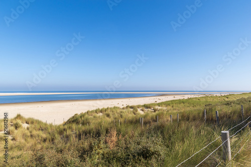 View over the blue sea with white beach and dunes with marram grass in the foreground. North Sea bss in the foreground. North Sea between Kijkduin and Ter Heijde  the Netherlands  called De Zandmotor.