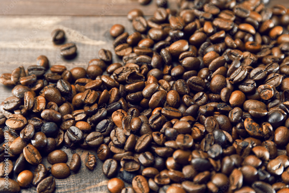 Grains of coffee scattered on a wooden brown background Grains of coffee scattered on a wooden brown background