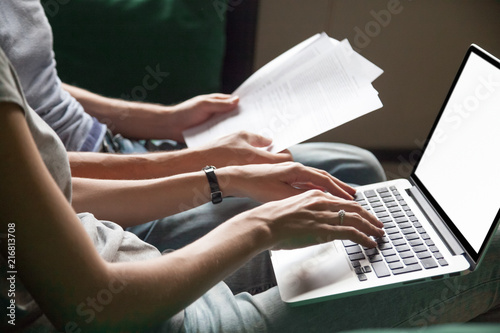 Close up of couple searching online information about legal document details with laptop, family studying important contract terms and conditions typing filling internet application form on website