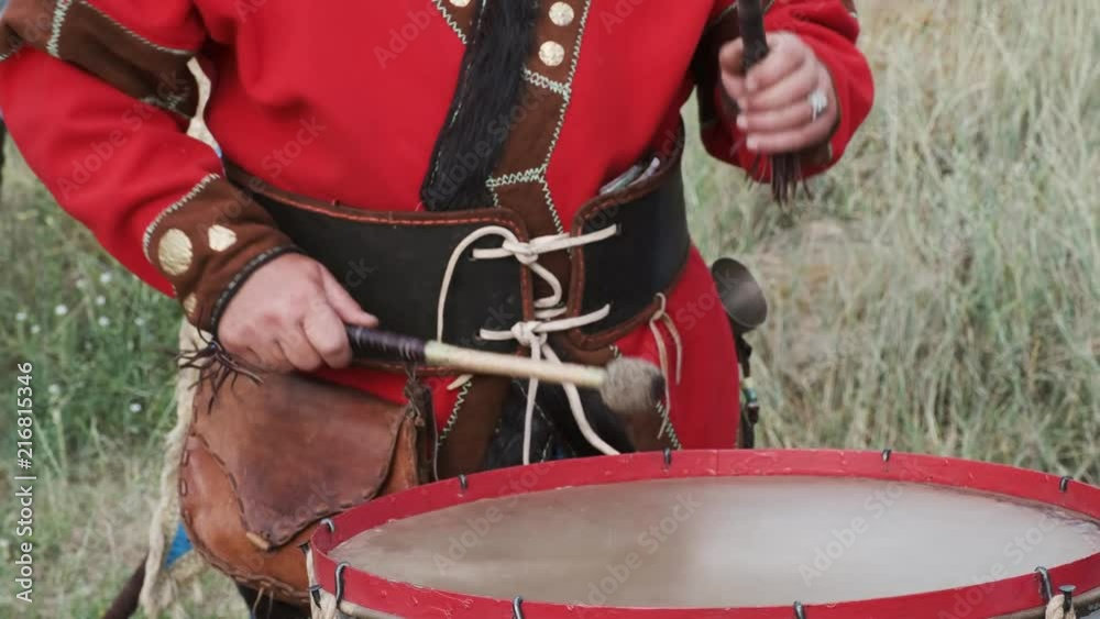 A view of a man in ethnic costume playing the drums
