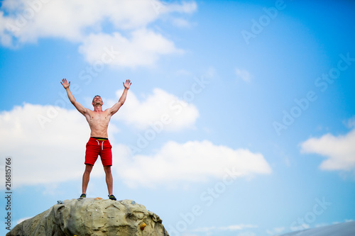 Photo of happy man climber on top of stone against blue sky