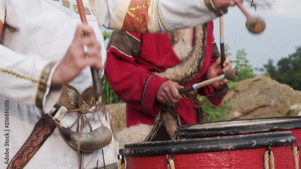 A view of two people in ethnic costumes playing the drums. Slow motion