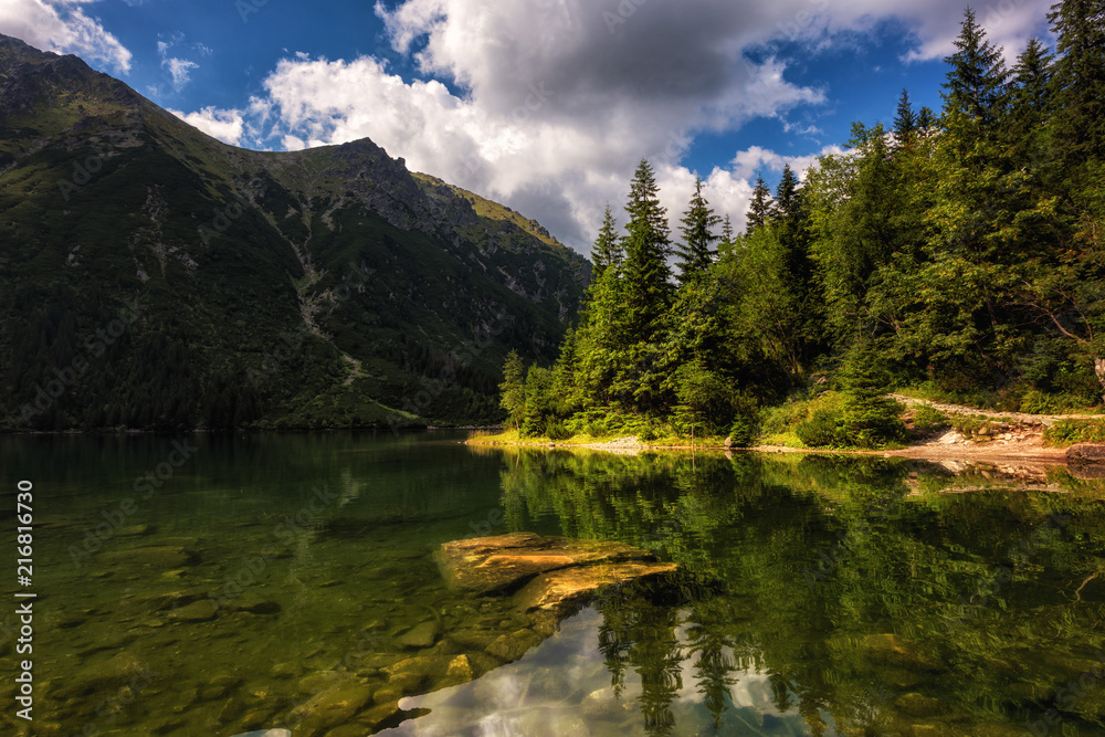 Beautiful alpine lake in the mountains, summer landscape with blue cloudy sky and reflection in crystal clear water, natural background, Morske Oko (Eye of the Sea), Tatra Mountains, Zakopane, Poland