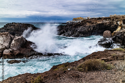 Seascape with black volcanic rocks, waves and splashes