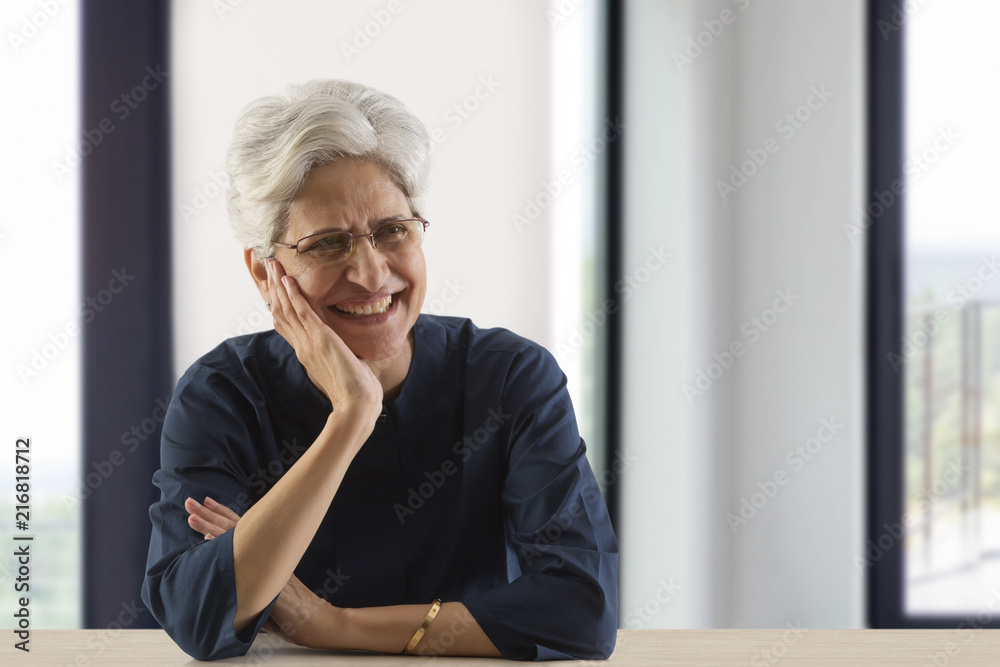 Smiling senior woman with hand on chin looking away Smiling senior woman with hand on chin looking away