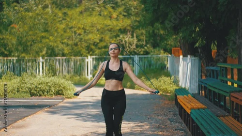 Young Athlete Woman in Comfortable Sport Outfit Jumping Rope on a Sports Field in the Park photo