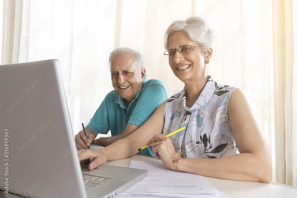 Senior couple doing paper work using laptop Senior couple doing paper work using laptop