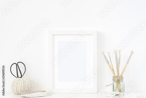 White frame mockup in interior. Frame mock up background for poster or photo frame for bloggers, social media, lettering, art and design. Indoor, frame on table, vintage elements. Summer sea mood