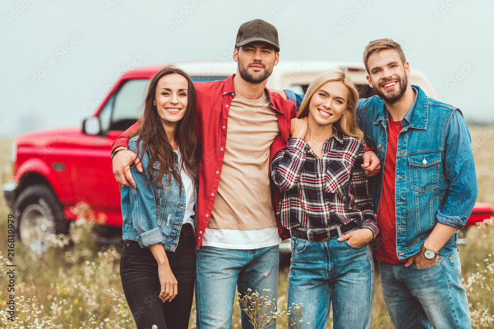 group of young people embracing and looking at camera in flower field group of young people embracing and looking at camera in flower field