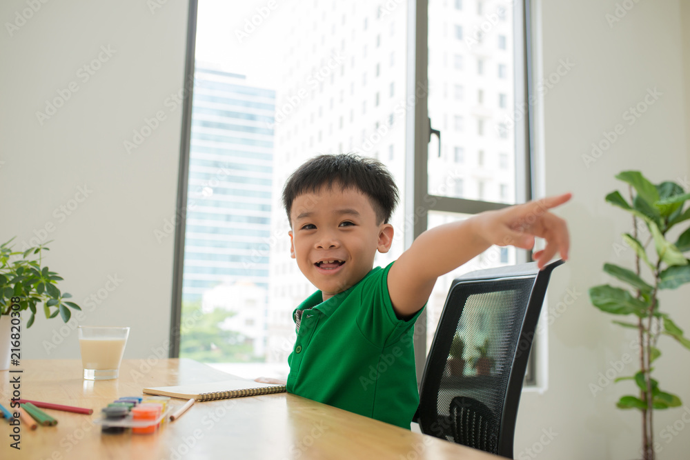 happy little boy laughing while studying and pointing at camera happy little boy laughing while studying and pointing at camera