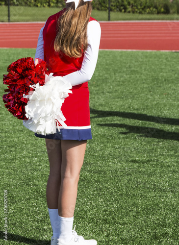 High school cheerleader with pompoms behind her back