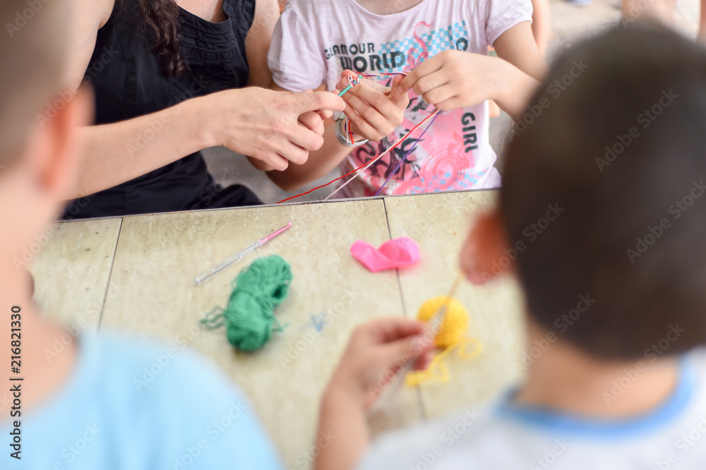 Hands of an adult and hands of a child knitting together Hands of an adult and hands of a child knitting together