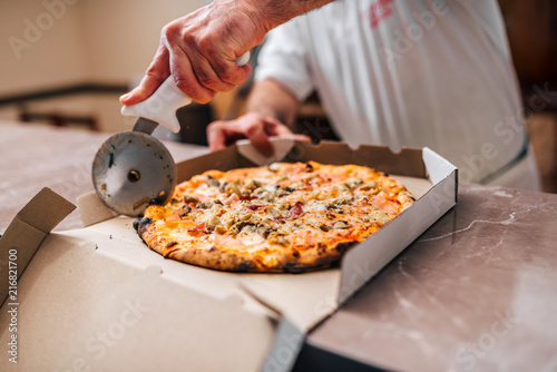 Chef cutting pizza for take away.
