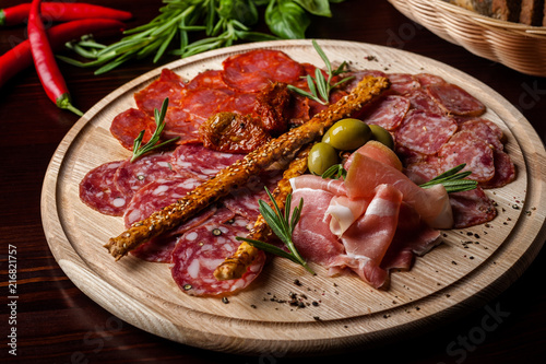 Fototapeta Naklejka Na Ścianę i Meble -  meat sliced proshto, salami, olives and pepper paprika on a wooden plate