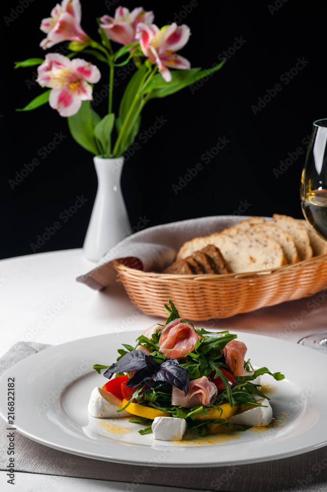 dish in the restaurant fresh salad with basil, prosciutto, tomato and mozzarella