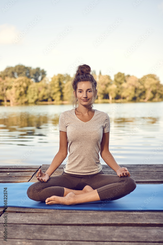 Fototapeta premium Junge Frau macht eine Yoga Übung am See