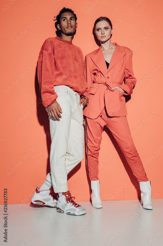 Casual couple in red leaning against a red wall