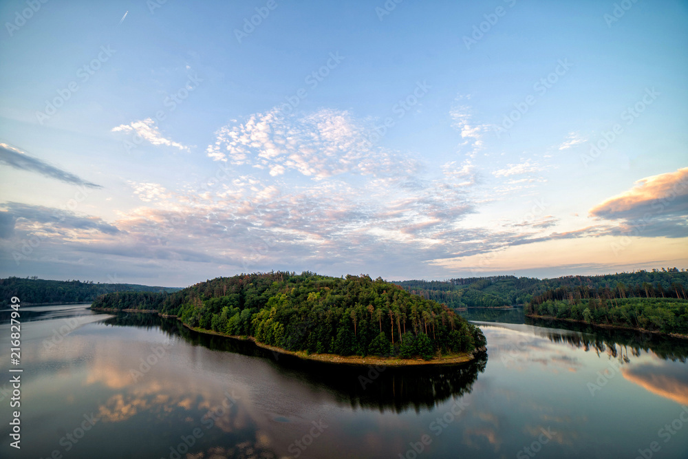 Obraz premium Colourful sunset over a lake. Summer scene of wide river landscape with setting sun.