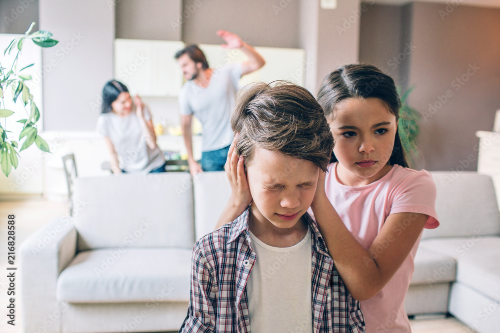 Girl stands behind her brother and keeps his ears closed with hands. Boy is terrified. He has eyes closed. Woman is trying to protect herself. Guy is going to beat her. He holds his hand up. Girl stands behind her brother and keeps his ears closed with hands. Boy is terrified. He has eyes closed. Woman is trying to protect herself. Guy is going to beat her. He holds his hand up.