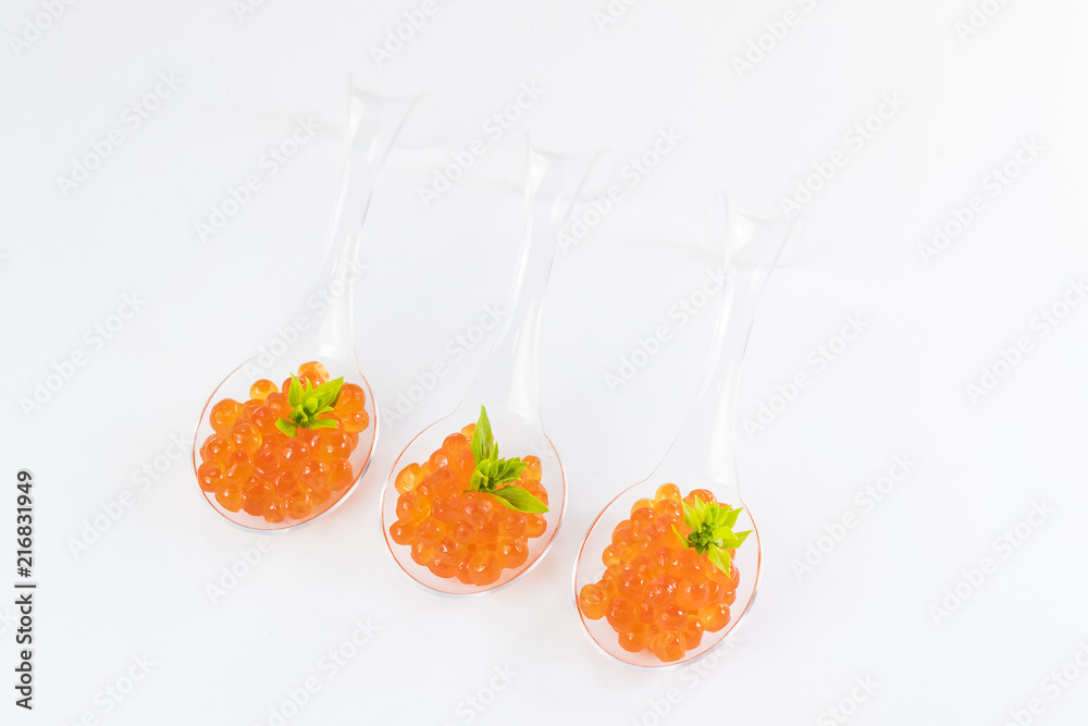 Plastic spoons with fish caviar on a white background. 