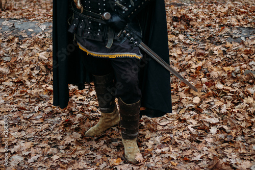 Medieval knight with sword in armor as style Game of Thrones in the forest.holds the sword