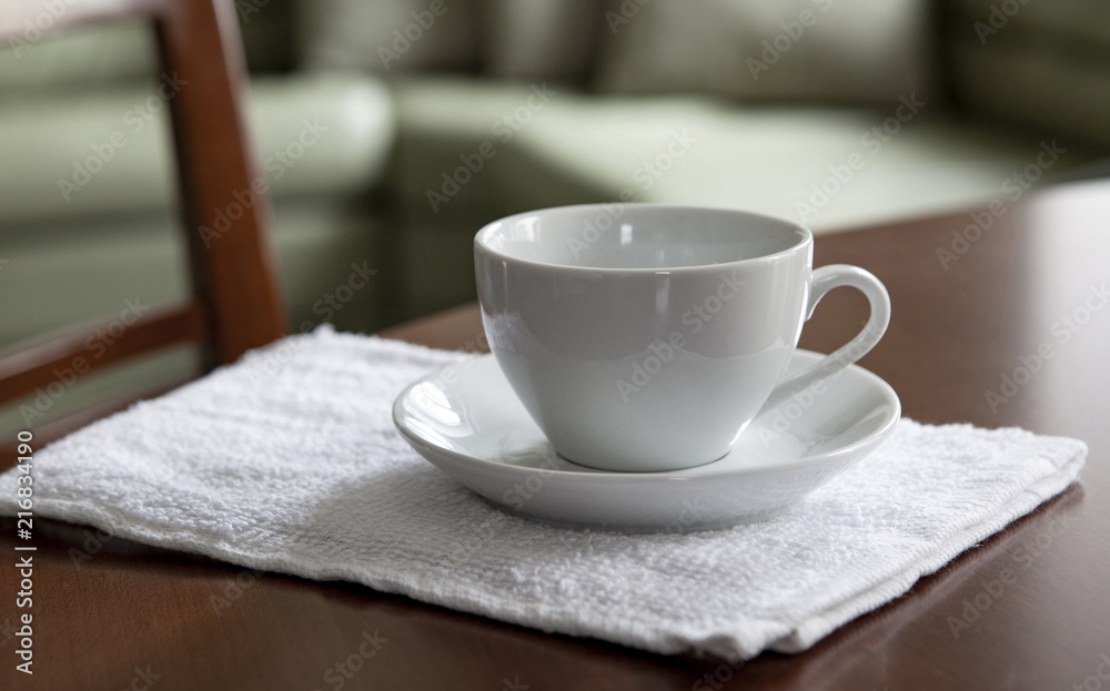 An empty white cup and a saucer stand on a wooden table. An empty white cup and a saucer stand on a wooden table.