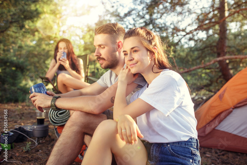 Party, camping of men and women group at forest. They relaxing against green grass. The vacation, summer, adventure, lifestyle, picnic concept