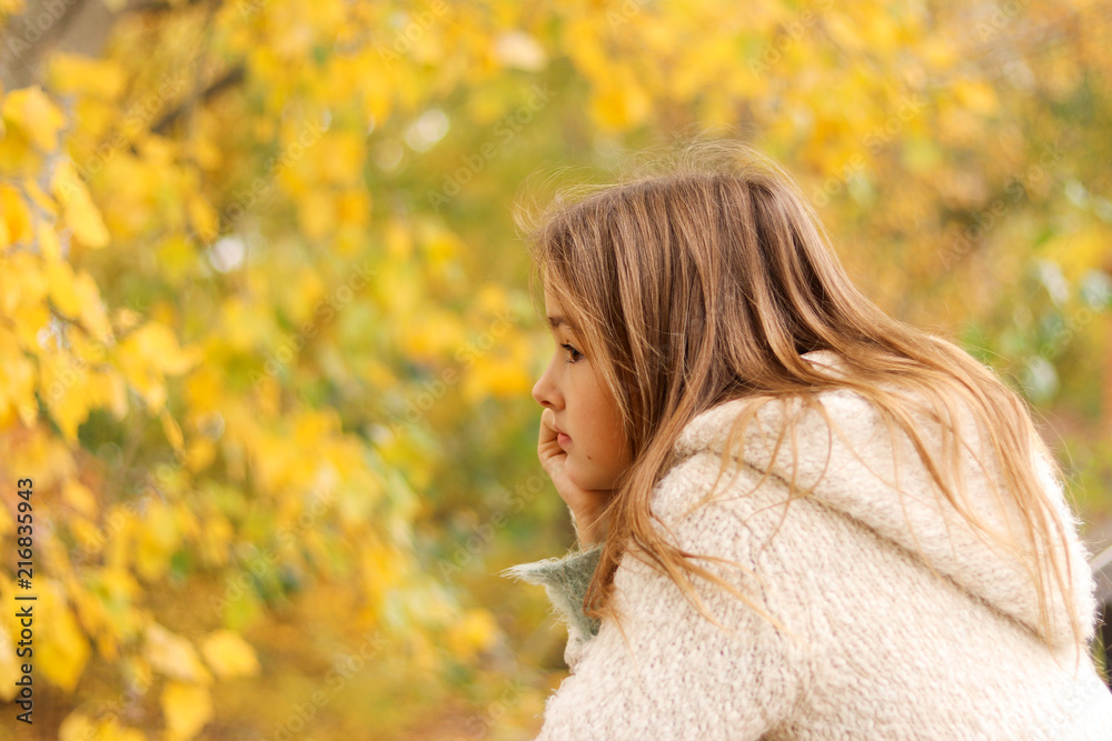 Beautiful pensive preteen girl daydreaming alone in autumn park with her chin on hand, yellow leaves at background. Fall melancholy concept. Hope. sadness. Loneliness. Beautiful pensive preteen girl daydreaming alone in autumn park with her chin on hand, yellow leaves at background. Fall melancholy concept. Hope. sadness. Loneliness.