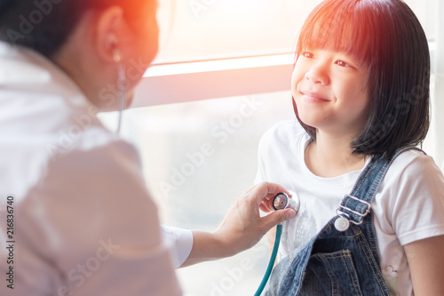 Professional general medical pediatrician doctor in white uniform gown listen lung and heart sound of Asia child patient with stethoscope: Physician check up Asian kid female after consult in hospital photo