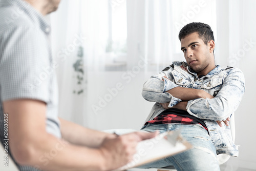 Offended spanish man in denim outfit during therapy with psychotherapist
