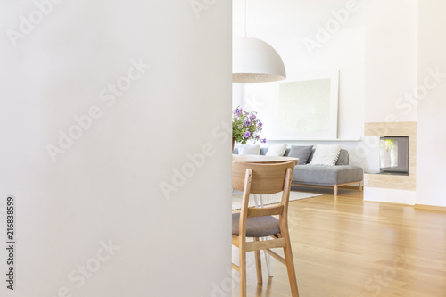 White empty wall with copy space in living room interior with chair and wooden floor. Real photo with a place for your light switch