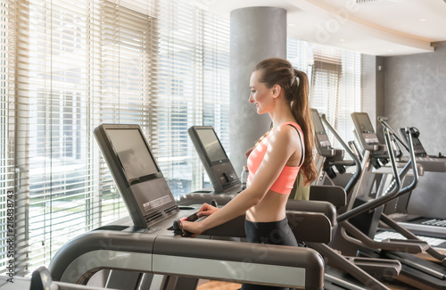 Young woman running on treadmills during workout session in the gym