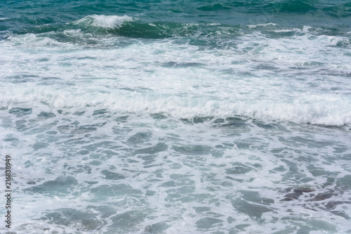 sea foam of the surf on the pebble beach shore