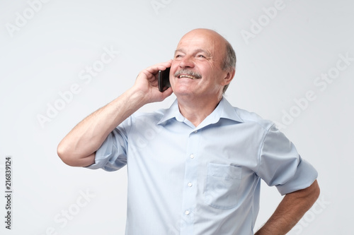 Portrait of happy european senior man talking on phone and smiling © Viktor Koldunov